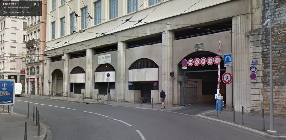 Pohled jen o&nbsp;pár metrů níže, než na&nbsp;minulém snímku – prostor bývalé spodní stanice Rue Terme v&nbsp;roce 2016 – vpravo v&nbsp;nové budově je vjezd do jednosměrného tunelu vedeného v&nbsp;trase bývalé lanovky, zcela vpravo je zřetelné i původní zdivo (foto: Google Streetview, 2016)