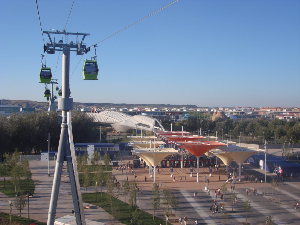 Vstup do areálu Expa (vstup byl na opačné straně než výstavní areál a je dnes demontován). Mohutná bílá konstrukce v pozadí je ona zmiňovaná lávka s názvem Pasarela del Voluntariado. 