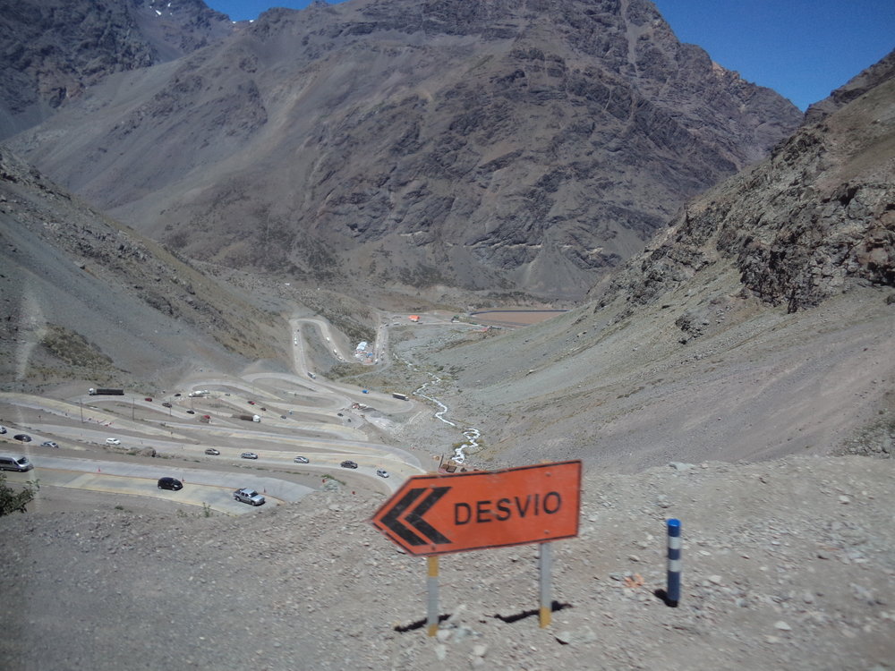 Překonávání takto náročného výškového rozdílu se transandská železnice spojující chilské město Los Andes s argentinskou Mendozou nevyhnula, cestu si ovšem razila delší trasou (a sice vlevo mimo záběr) než dnešní silnice č. 60. Je velká škoda, že 248 km dlouhá trať, kterou stavěly pod taktovou anglické společnosti od konce 80. let 19. století na obou stranách argentinské-chilské hranice tisíce dělníků  (obě země se přitom v té době ještě dohadovaly o podobu svých hranic!), vydržela v provozu jen sotva tři čtvrtstoletí (1910– 1984). O jejím konci rozhodly roku 1984 rozsáhlé laviny, které ji na řadě míst poškodily. Argentinská strana sice své poškozené úseky částečně opravila, chilská ale nikoli, a tak se od té doby už nejezdí. Na chilské straně je pro potřeby nákladní dopravy v provozu jen úsek Los Andes (km 248) – Río Branco (km 214), neboť v Río Branco je odbočka do měděných dolů společnosti Codelco. Záběr byl pořízen na chilské straně na jednom z tzv. „ šneků“ , neboli serpentinách. Dodejme ještě, že ve městě Los Andes museli cestující kvůli odlišným rozchodům tratí přestupovat.