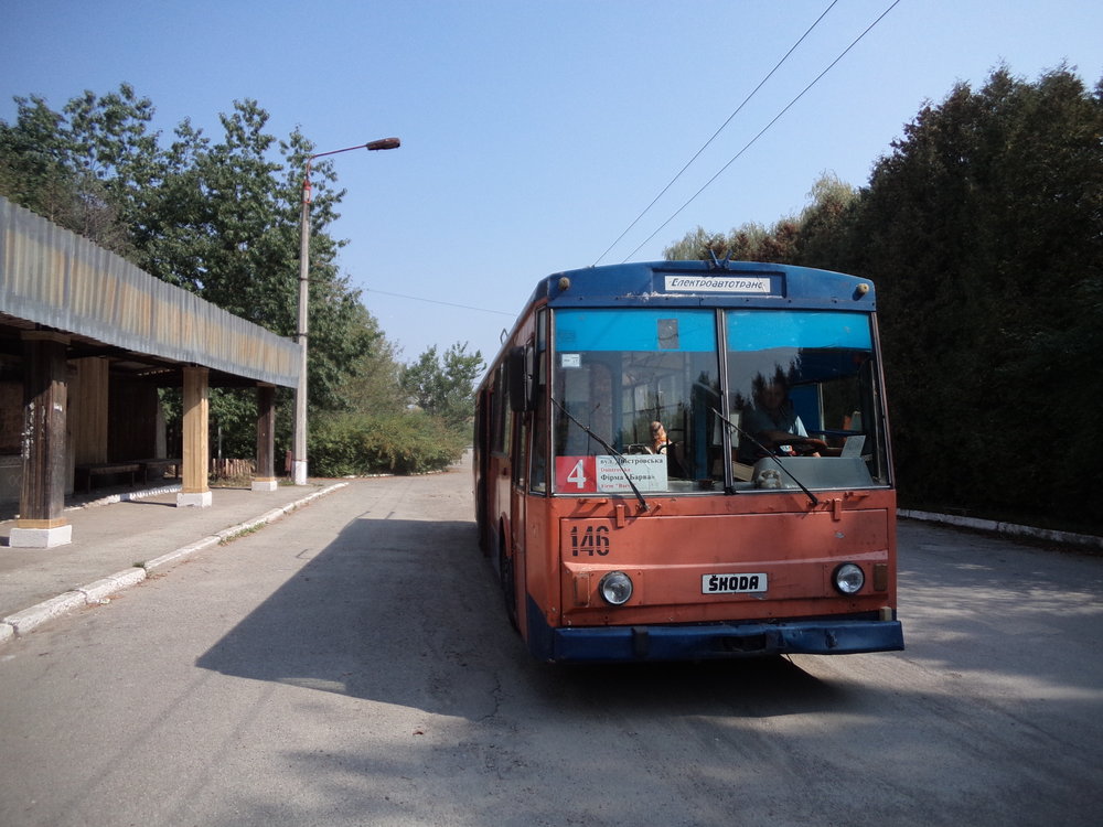Konečná zastávka Firma Barva v detailu. Trať vedená do těchto míst byla otevřena v roce 1989 a přinejmenším její koncový úsek má své nejlepší časy za sebou. Zřejmě jen díky tomu, že trolejbusy obsluhují po trase nedalekou vesnici Jamnycja, u které se mimochodem nachází jedna z největších a nejmodernějších cementáren Ukrajiny, přežívá trolej nad silnicí H09 do dnešních dnů. Na snímku zobrazený vůz ev. č. 146 patří do série vozů typu 14Tr02/6 pořízené na konci 80. let a vedené pod ev. č. 141 –156. V současnosti nezasahuje z 16 vozidel do provozu jen jedno, ev. č. 145, jež je už postupně likvidováno.