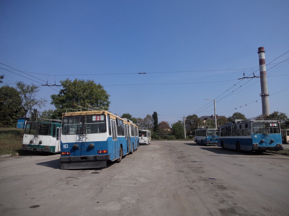 V polovině 90. let přišly do Ivano-Frankivsku čtyři článkové vozy JUMZ T1, které obdržely ev. č. 161–164. Vozům ev. č. 161 a 164 byla později odňata zadní část a po příslušných úpravách se z nich staly sólo trolejbusy vedené pod stejnými ev. č., avšak už jako přeznačený typ JUMZ T1P. Oba tyto zkrácené vozy jsou přitom na snímku přítomny. Z dvou zbývajících článkových vozů jezdí už jen jeden, a to ten nesoucí ev. č. 163. Na pravé straně vzadu si ještě povšimněme vozu s ev. č. 157. Jedná se o jeden ze sedmi krátkých vozů (ev. č. 157, 165–170) typu JUMZ T2, které do Ivano-Frankivsku zavítaly ve stejném období jako vozy článkové. Dnes už jsou vypravovány jen tři z nich.