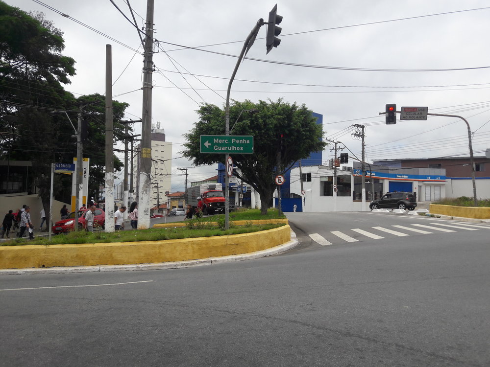  Při příjezdu z centra (tj. od terminálu Aricanduva) k terminálu Penha vidí řidič trolejbusu přibližně toto. Terminál je umístěn vlevo od stromoví na snímku, a to na jakémsi ostrůvku. Trolejbus tedy odbočí vlevo, zajede do terminálu, obkrouží tzv. kolečko po směru hodinových ručiček (stopa tohoto “kolečka” je na snímku vidět v pozadí), překříží stopu, po které přijel na terminál, a dále putuje jinou ulicí zpět do centra, jak už bylo ostatně popsáno na předchozím snímku.    