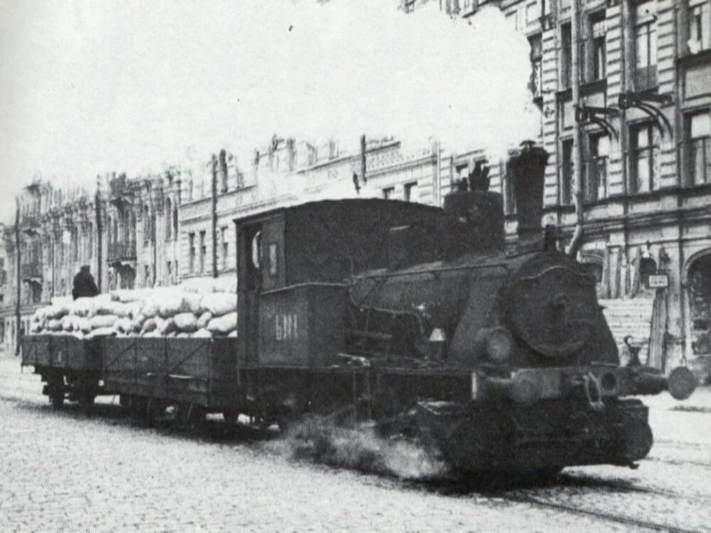 Během blokády Leningradu sloužily na tramvajových tratích také parní lokomotivy. Zde vidíme nákladní vlak při přepravě mouky. Parní lokomotivy ve spojení s tramvajovými vozy se však měly používat také pro přepravu osob v lokalitách, kde nebylo možné zajistit napájení. (archiv: GUP Gorelektrotrans)