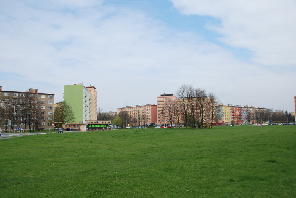 Část travnaté plochy se dodnes zachovala. Zde byla původně navržena tramvajová smyčka, která měla být na okraji plánovaného náměstí, a to nejspíše rovněž pod povrchem (s ohledem na známé návrhy architektonického řešení lokality). Šikmě postavené budovy jsou začátkem (či koncem) Hlavní třídy, která měla do náměstí ústit.  (foto: Libor Hinčica)