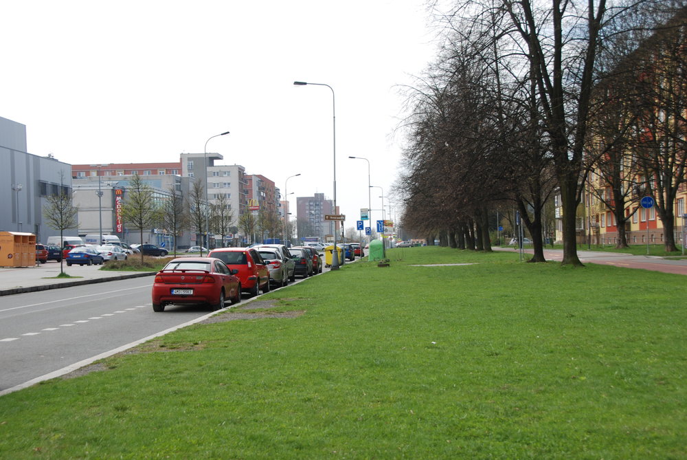 Opačný pohled na ulici Francouzskou a rozsáhlý pás zeleně. Nalevo jde vidět část zástavby vybudované z větší části po roce 1990. Namísto reprezentativního náměstí vznikla obytná zástavba, obchodní středisko a hypermarket. Šance na důstojné propojení dvou stavebních obvodů Poruby byla ztracena. (foto: Libor Hinčica)