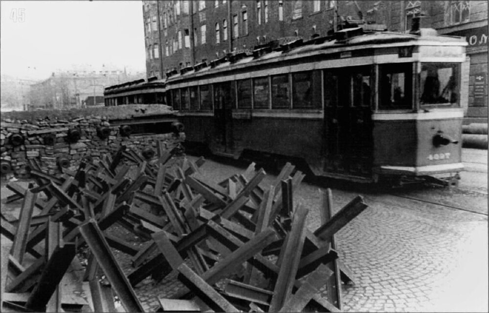 Město se připravovalo na možný boj přímo v jeho ulicích. Tramvaj projíždí v listopadu 1941 kolem jedné z připravených blokád. Protitankoví ježci z kolejnic byli mimochodem vyráběny mj. pracovníky tramvajových dílen. (archiv: GUP Gorelektrotrans)