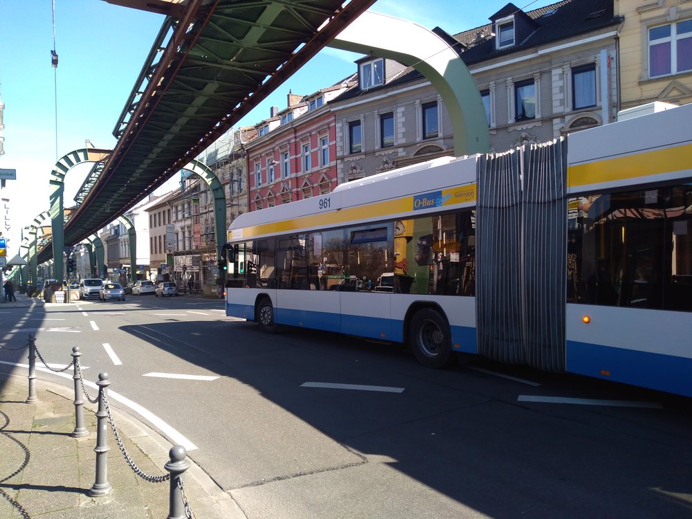  Trolejbus kdysi po příjezdu do Wuppertalu dojel k výchozí zastávce místní slavné visuté dráhy (za zády fotografa) a vracel se zpět. U visuté dráhy byla trojúhelníková bloková smyčka, na které trolejbusy měnily směr. Dne 4. srpna 2014 začaly trolejbusy jezdit k vohwinkelskému nádraží s pomocí dieselového pohonu a velká část smyčky, ze které trolejbus právě vyjíždí, tím zůstala nevyužita. 