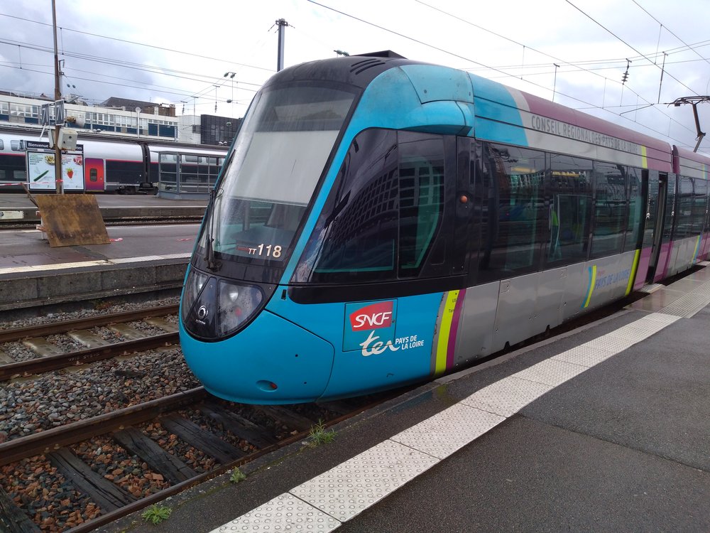 Na snímku z 26. 4. 2019 vidíme vlakotramvaj na nantském hlavním nádraží, kde má pro sebe přizpůsobenu koncovou část jednoho z nástupišť. Přístup k tramvaji je nekrytý, což není za deště zrovna pohodlné řešení.