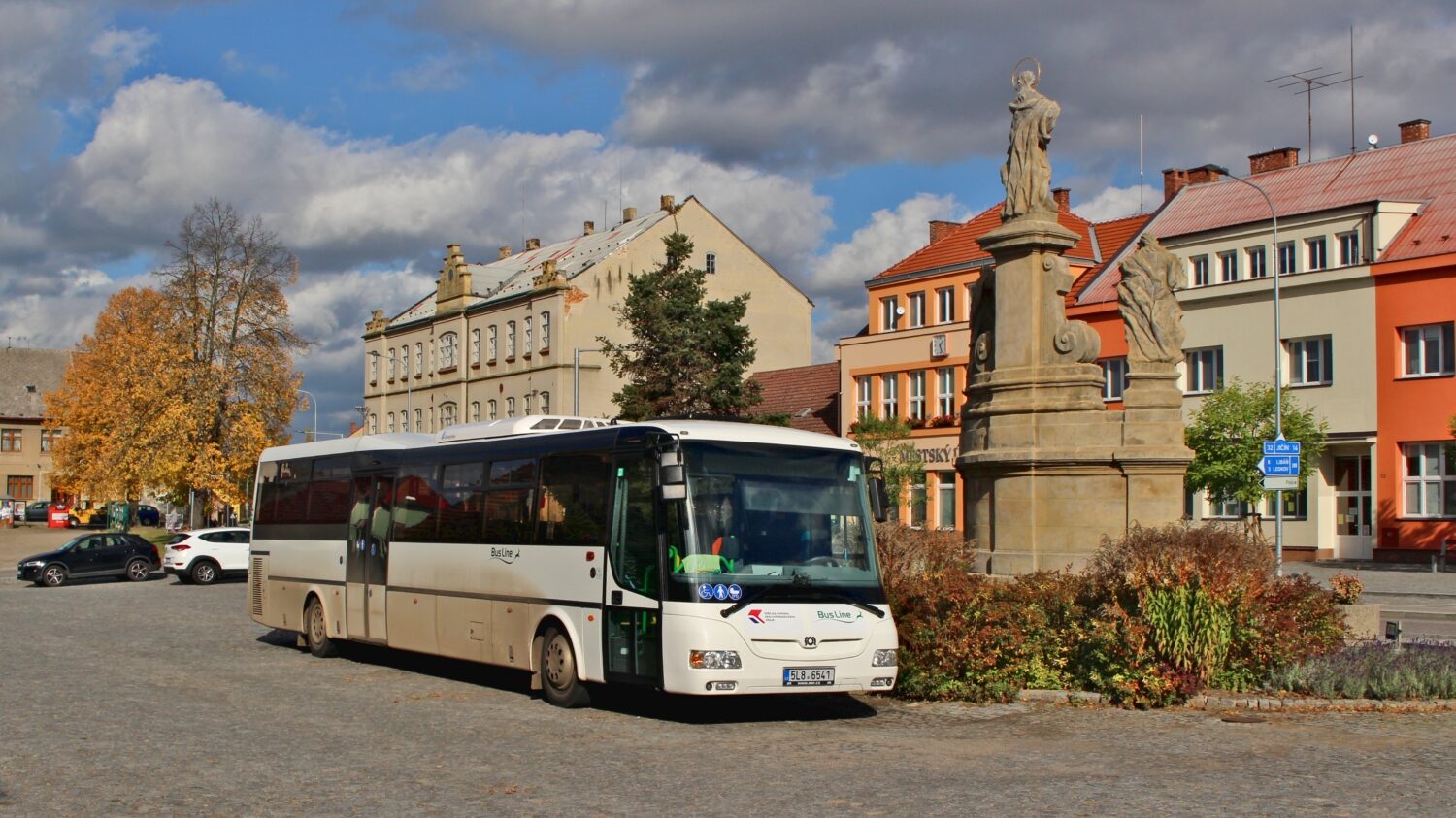 Autobus SOR CN 12,3 společnosti BusLine zachycený na náměstí v Kopidlně společně s barokním sousoším Panny Marie, sv. Jana Nepomuckého a sv. Josefa z roku 1720. (foto: ROPID)